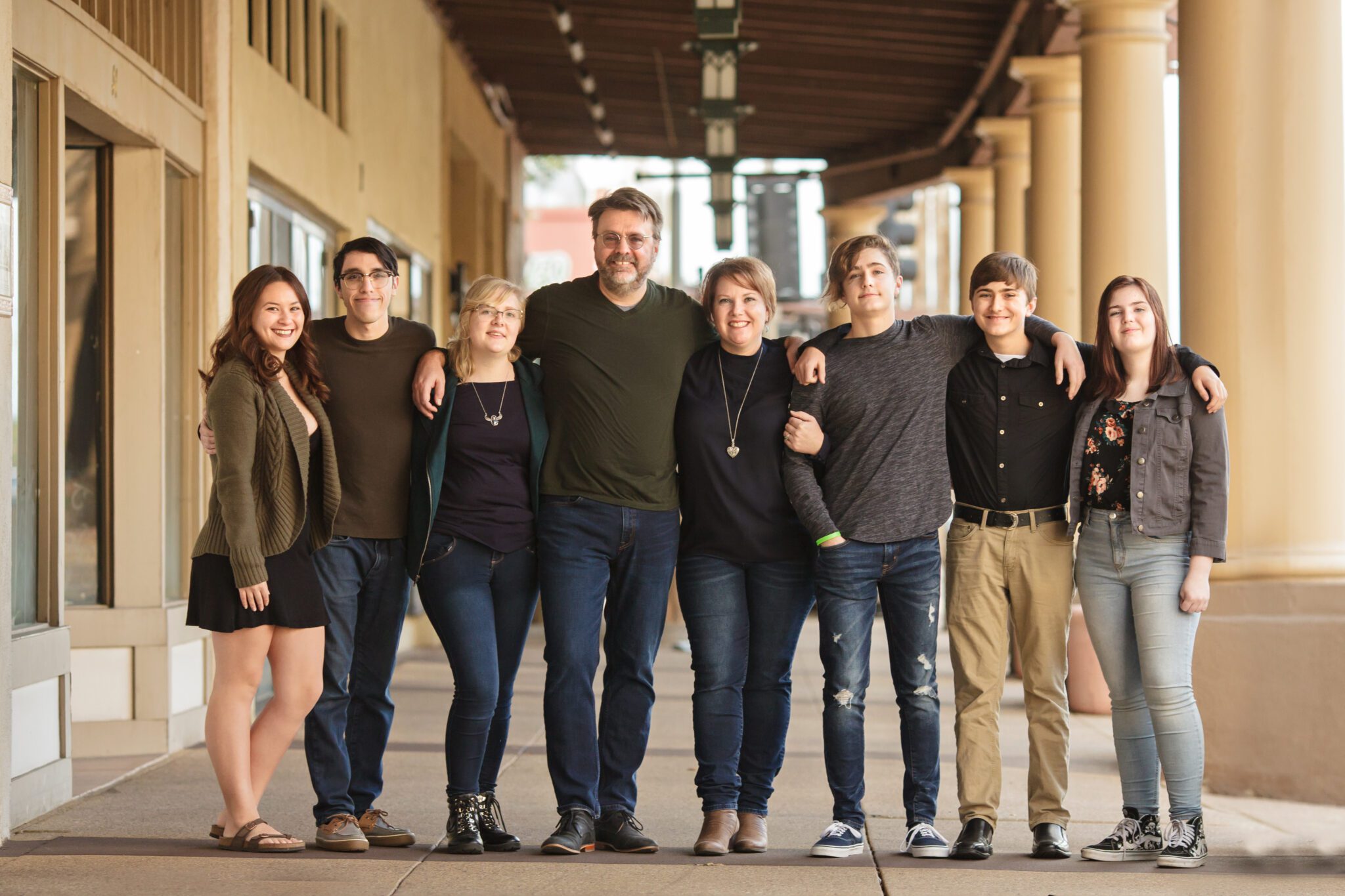 Large blended family posed in front of historic building with relaxed, modern vibe