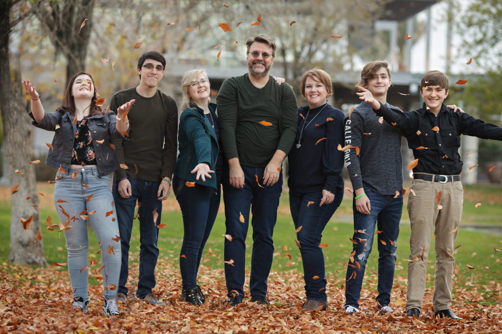 Blended family of eight with six teens and adult kids smiling together in Downtown Chandler