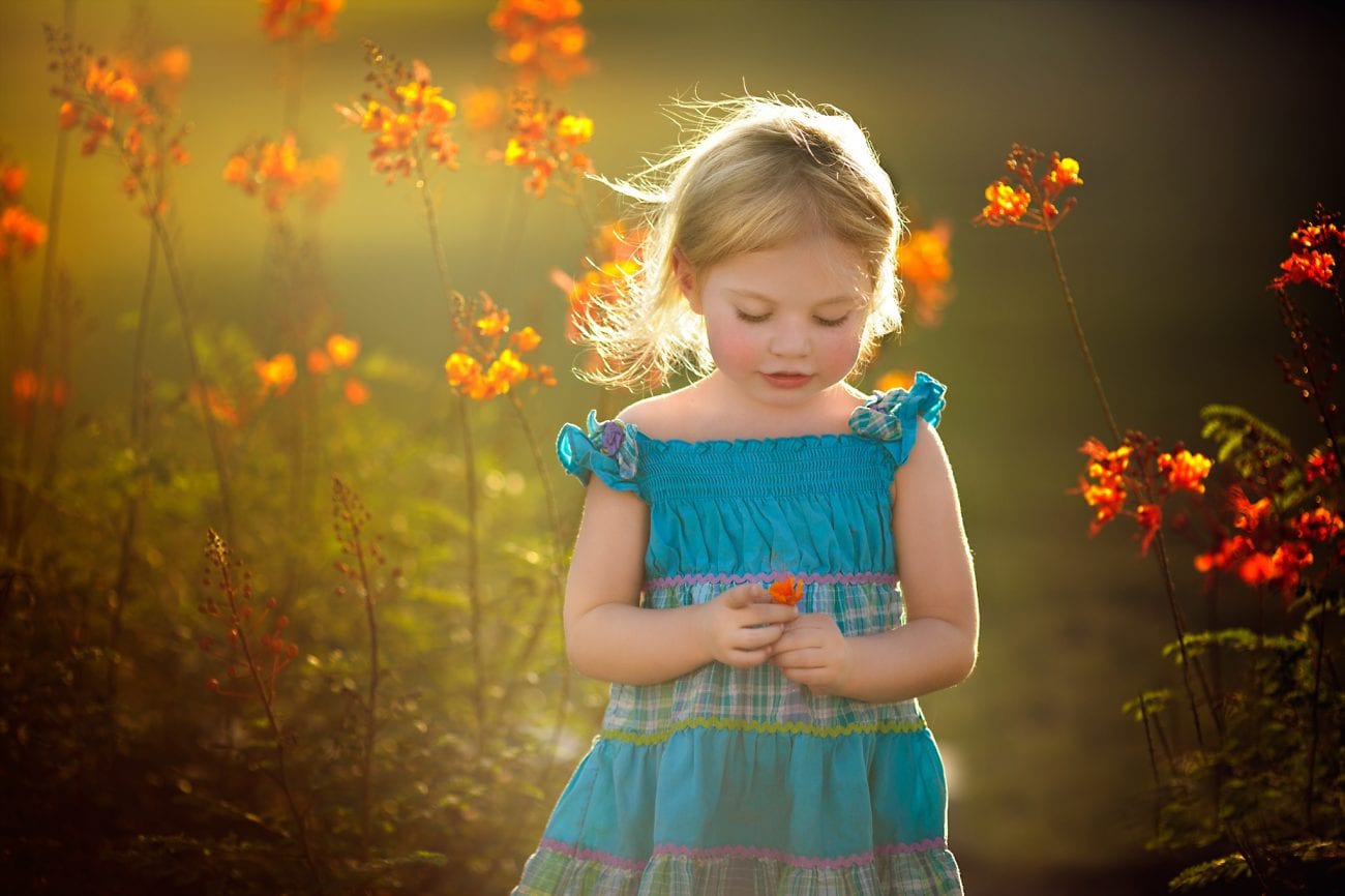 Portrait of a 4 year old girl in organge flowers with her hair blowing in the wind
