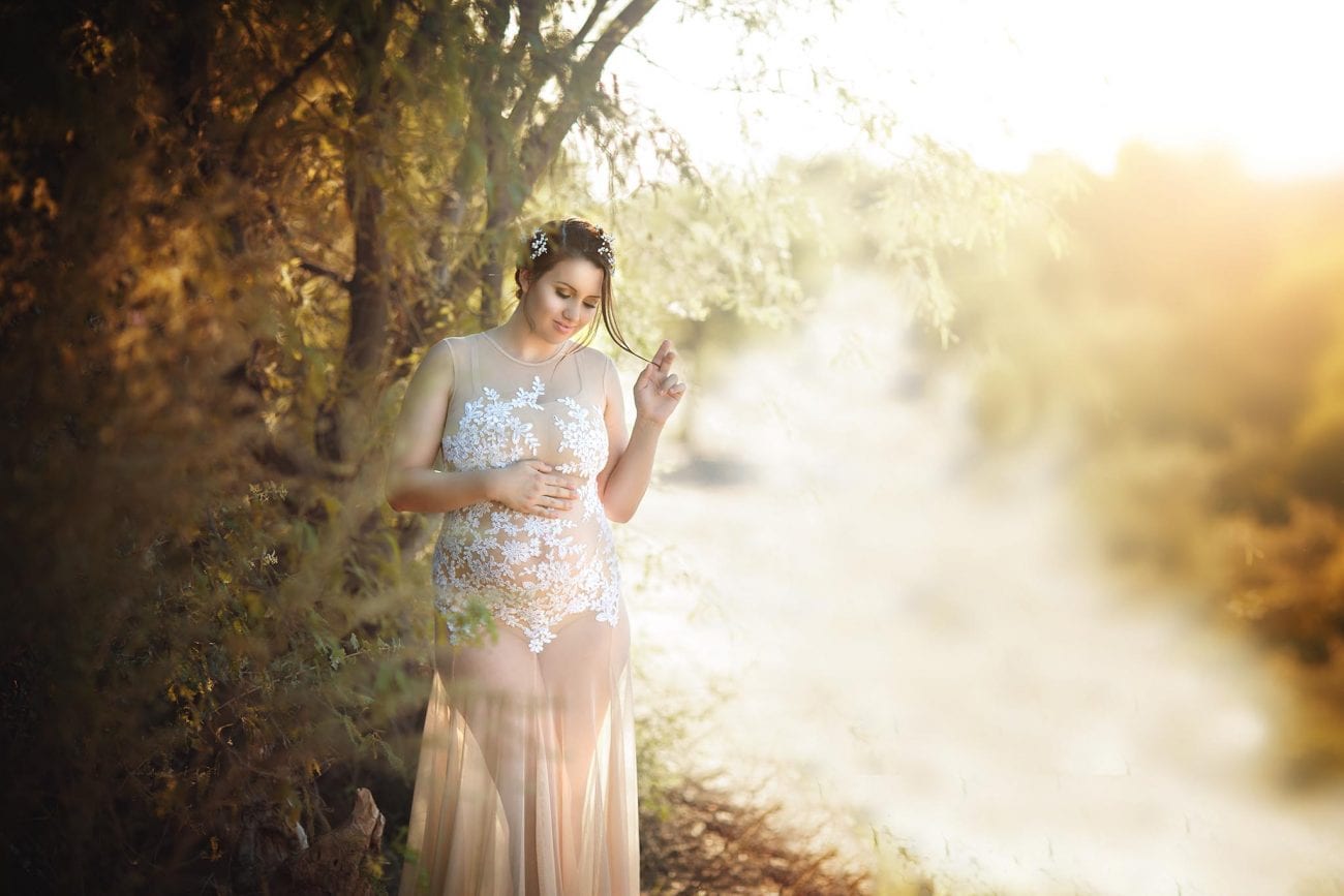 Maternity photography of 8 month pregnant woman taken near Central Phoenix. Model is wearing a c=beautiful nude gown and twirling hair