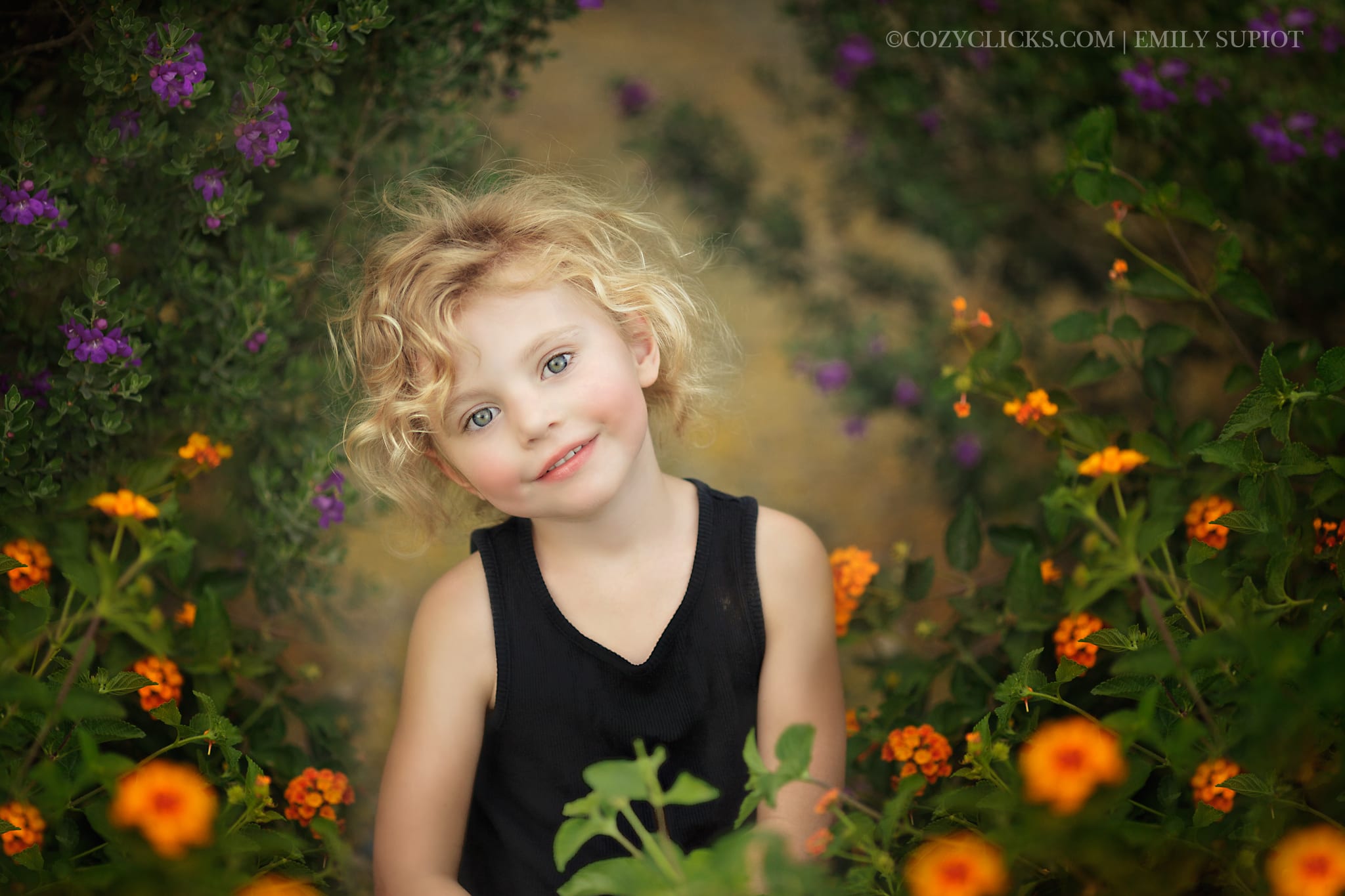 Young girl sitting in a field of orange and purple springtime flowers in the desert