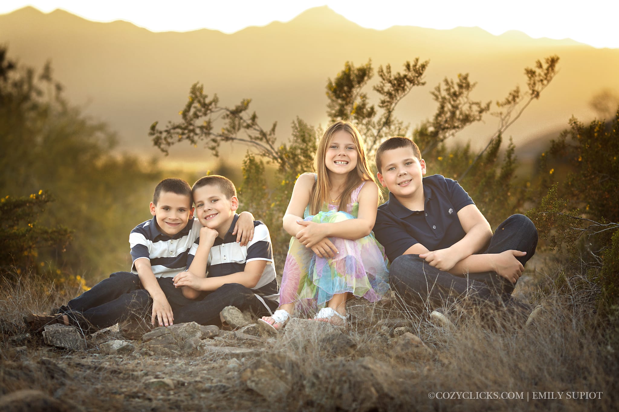 Four brothers and sisters under age 12 sit in the desert with the mountains behind them
