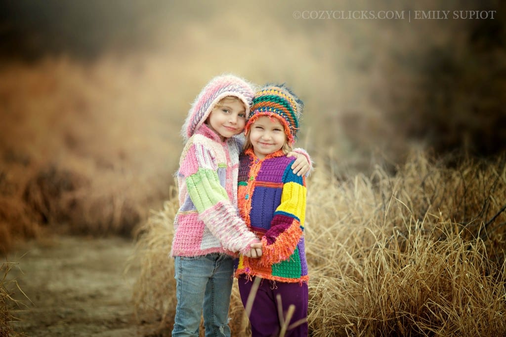 Sisters holding hands and posing for portrait near Ahwatukee in bright colored handmade sweaters and hats