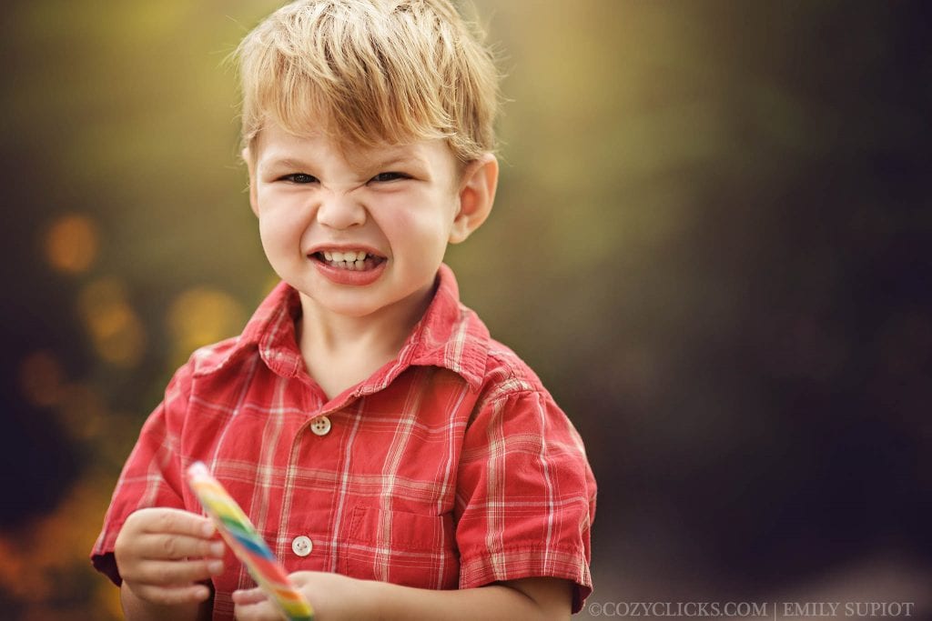 Two year old portriat of boy smiling with a lolipop in Phoenix, AZ neighborhood park
