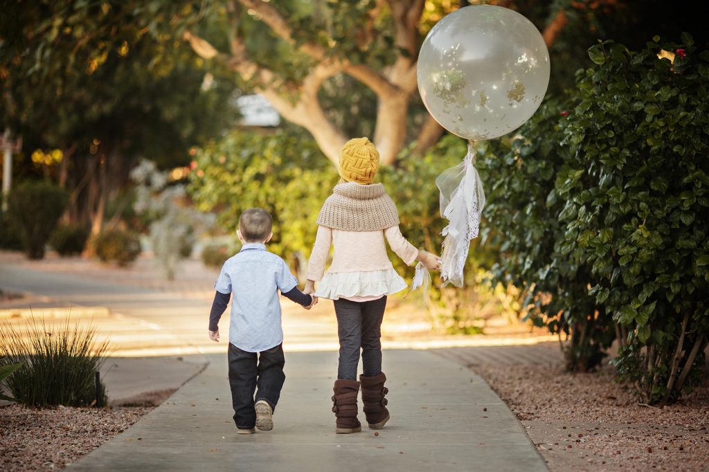 Two siblings walking with balloons for a photos at the Scottsdale Civic center.