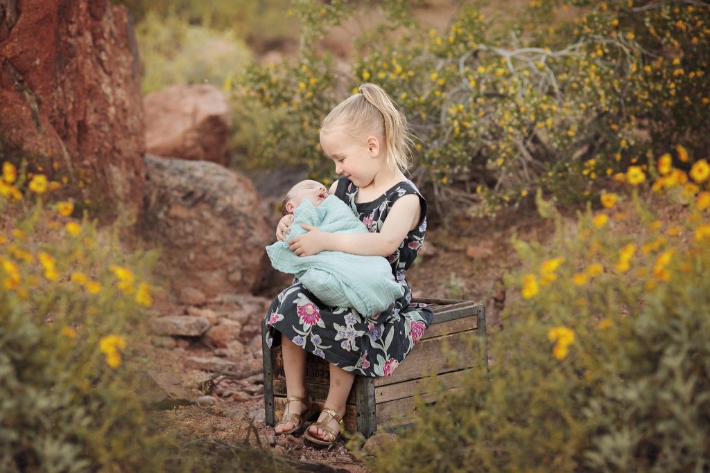 Sibling and newborn photo taken outdoors by Arizona wildflowers